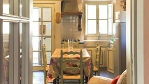 A cozy kitchen with wooden beams, a dining table with chairs, and a white sofa. - 4 bed apartment with pool (Pontremoli)
