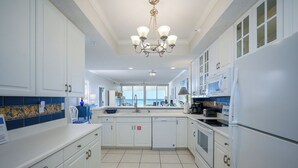 A modern kitchen with white cabinets, a dishwasher, a microwave, and a sink. - Navarre Beach Regency 304 - Eat. Beach. Sleep. Repeat. (Navarre)
