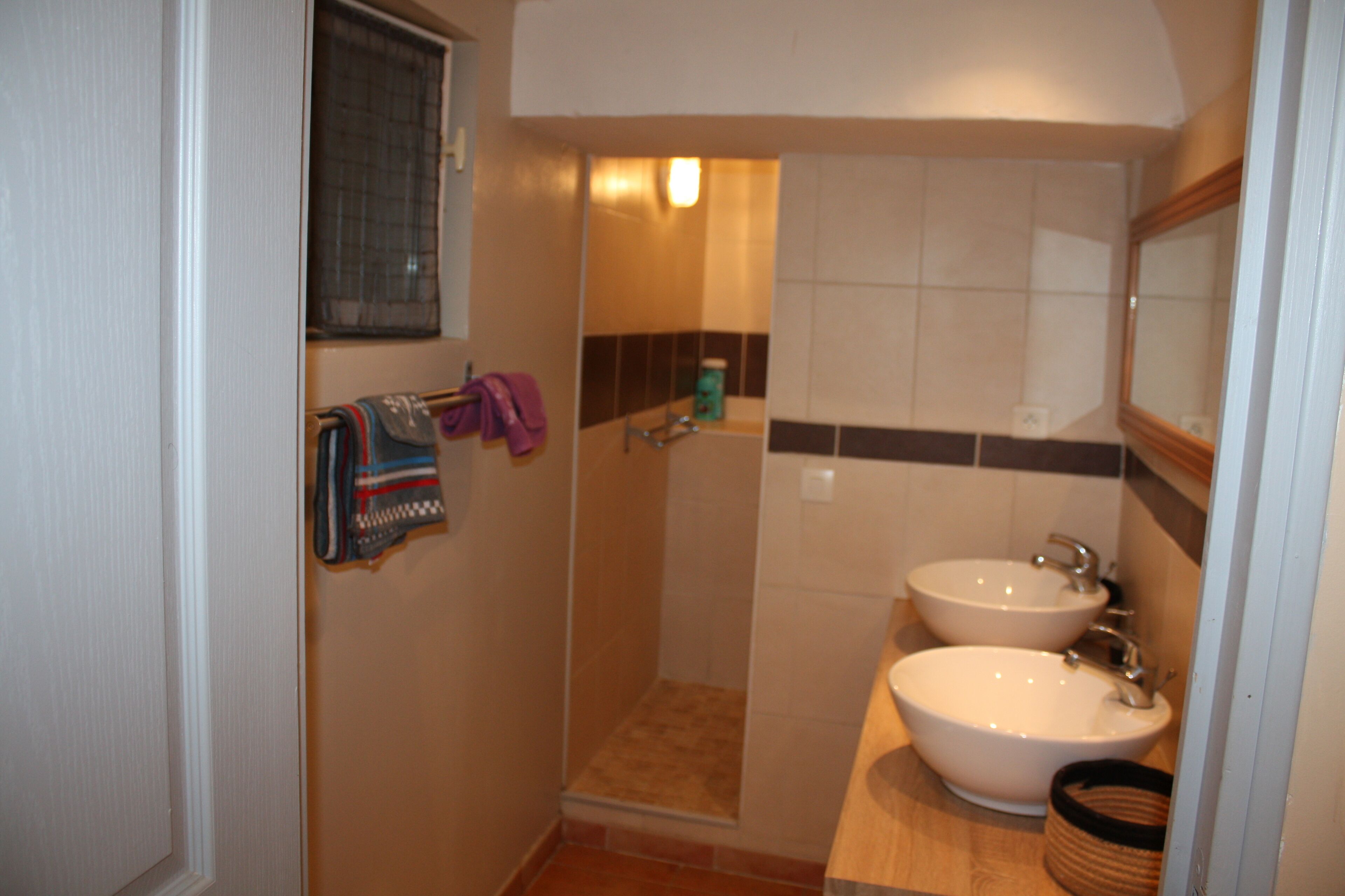 Ein Badezimmer mit zwei Waschbecken, einer Dusche und einem Handtuchhalter mit Handtüchern.