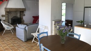 A cozy living area with a stone fireplace, a grey sofa, and a dining table with chairs.