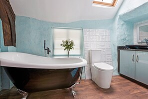 Een badkamer met een vrijstaand bad, toilet en kast.