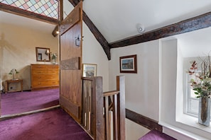 Traditional charm fills this room with a wooden staircase, dresser, and framed artwork.