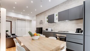Una cocina moderna con una mesa de comedor de madera, sillas blancas y armarios grises.