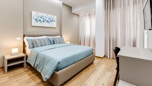 Un dormitorio moderno con una cama grande, mesitas de noche, un escritorio y un cuadro en la pared.