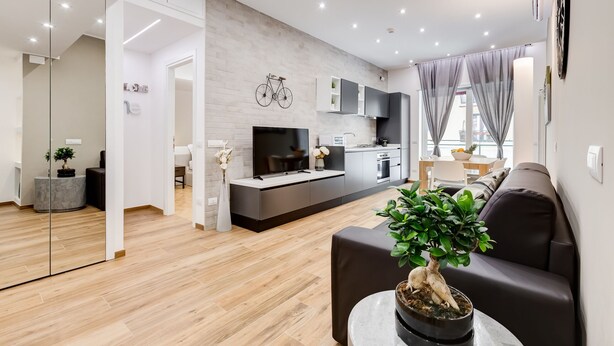 Una sala de estar moderna con un televisor grande, un sofá y una mesa de centro con una planta.