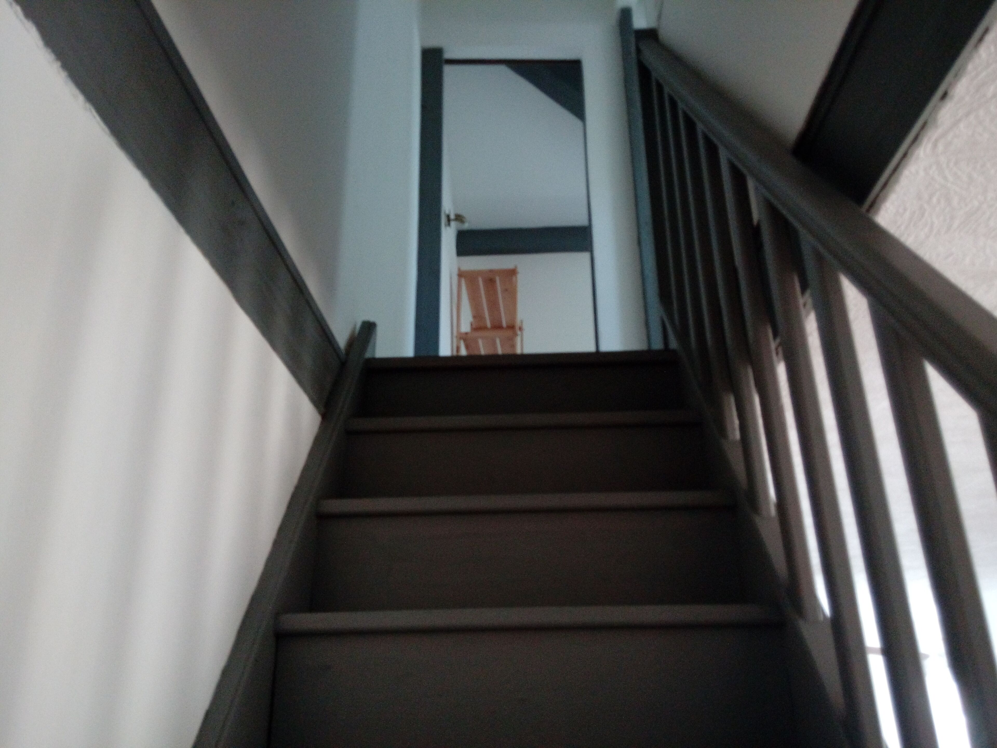 A staircase with wooden steps and black handrails, leading to a door with a white frame.