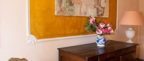 Una habitación con piso estampado, un armario de madera, una silla y un cuadro enmarcado en la pared.
