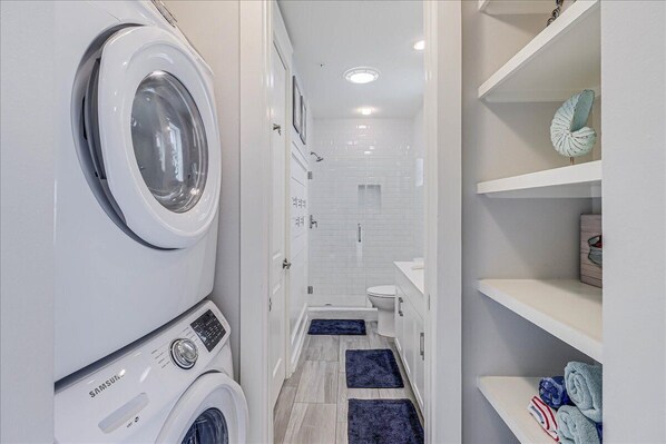 Un espace buanderie équipé d’un lave-linge et d’un sèche-linge Samsung, d’une douche et de toilettes.