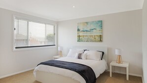 A bedroom with a bed, white walls, a beach painting, and two bedside tables with lamps. - 31 McMillan Crescent, Dalmeny (Dalmeny)