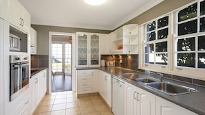 A modern kitchen with white cabinets, stainless steel appliances, and a large window providing natural light. - 31 McMillan Crescent, Dalmeny (Dalmeny)