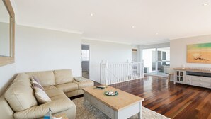 A spacious living room with a beige sofa, a wooden coffee table, and a white railing in the background. - 31 McMillan Crescent, Dalmeny (Dalmeny)