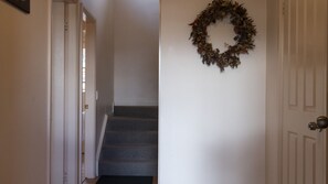 Ein Flur mit Teppichstufen, einer weißen Tür und einem Kranz an der Wand.