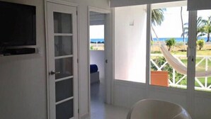 Una habitación con un ventanal grande, una puerta y una hamaca afuera.