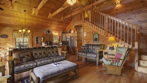 Interior acogedor de una cabaña de madera con escalera, sofá y zona de comedor.