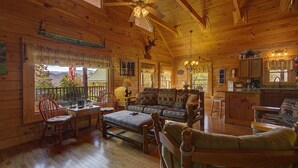 Interior de una cabaña de madera con comedor, sofá y cocina.