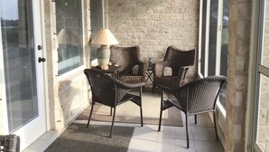 Une terrasse couverte, aménagée avec des meubles en osier, une table et une lampe.