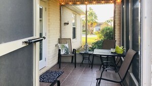 Eine überdachte Terrasse mit Deckenventilator, Lichterkette und Tisch mit Stühlen.