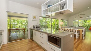A modern kitchen with a central island, white cabinetry, and a view of greenery outside.