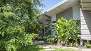 A modern house with a covered porch, surrounded by lush greenery and a well-maintained lawn.