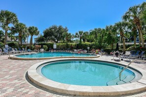 A pool area with multiple circular pools, lounge chairs, and palm trees. - Indulge at Harbor Towers | Resort-style amenities (Siesta Key)