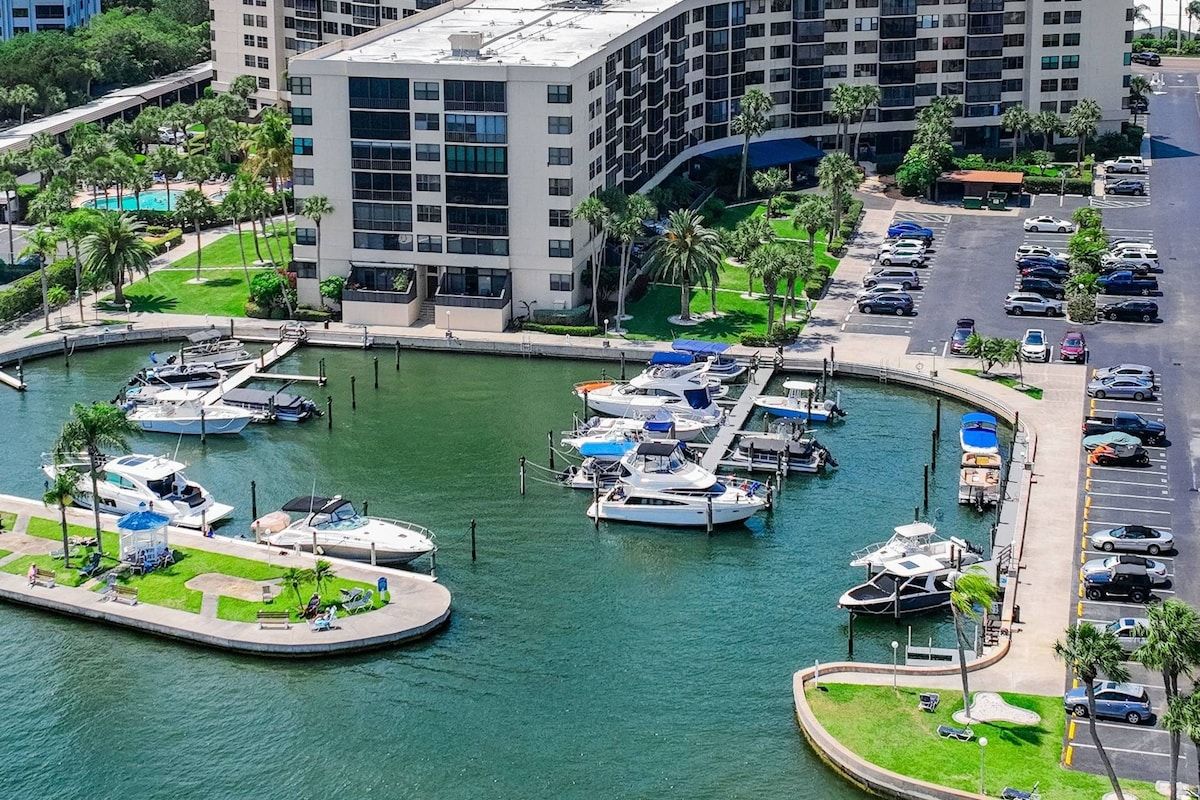 A marina with boats docked, a parking lot, and a building with multiple floors.