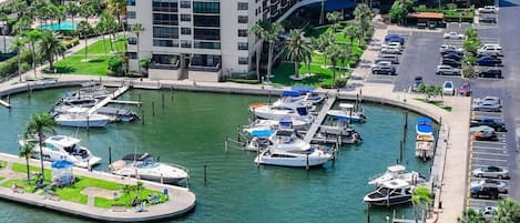 Marina com barcos atracados, estacionamento e um edifício com vários andares.