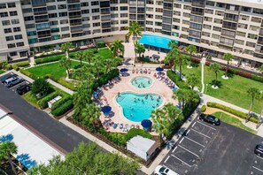 A hotel with a central swimming pool surrounded by lounge areas and palm trees. - Indulge at Harbor Towers | Resort-style amenities (Siesta Key)
