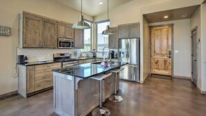 A modern kitchen with a central island, stainless steel appliances, and wooden cabinetry. - Upscale Moab Townhome w/ Hot Tub: 20 Min to Arches (Moab)