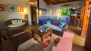 A cozy living room with wicker furniture, a blue sofa, and a wooden ceiling. - Las Palmas in Kitten's Warf (Providencia)