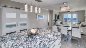 A modern kitchen with a granite countertop, pendant lights, and a large island. - Inn at Crystal Beach 308 * Gulf Front with Beach Chair Set. Onsite dining! (Destin)