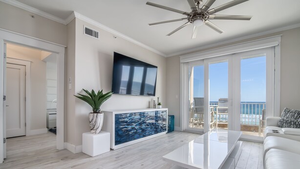 A modern living room with a flat-screen TV, a large aquarium, and a balcony with a view of the ocean. - Inn at Crystal Beach 308 * Gulf Front with Beach Chair Set. Onsite dining! (Destin)