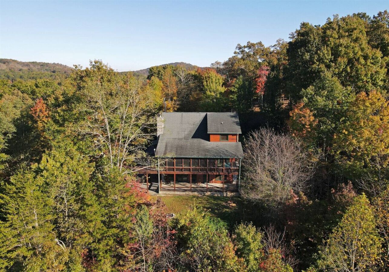 A house surrounded by dense forest with a large porch area.