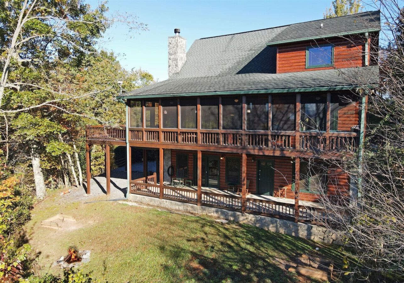 A two-story log cabin with a balcony and a stone chimney.