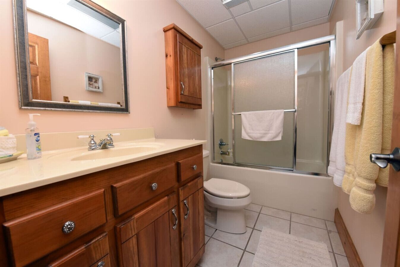Une salle de bain avec un meuble-lavabo en bois, un évier, des toilettes et une douche à parois de verre.