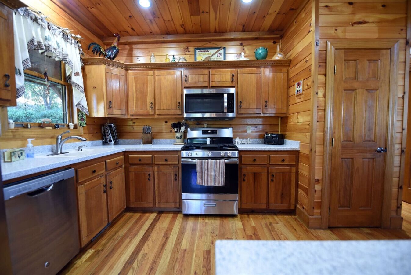 Une cuisine de style rustique, avec des éléments en bois, comprenant un four à micro-ondes, une cuisinière et un évier.