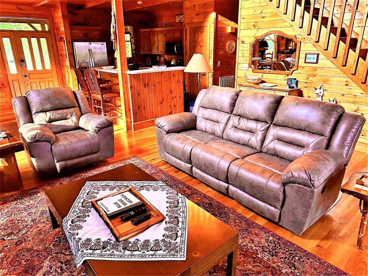 Un interior de madera con un sofá, un sillón y una mesa de centro con un control remoto.