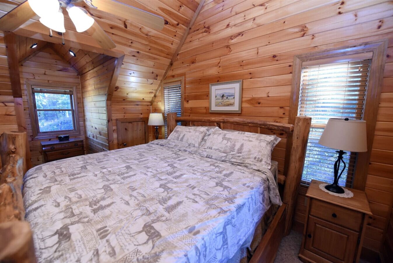 Une chambre confortable dans un chalet en bois, avec un lit, des tables de chevet et une fenêtre équipée de stores.