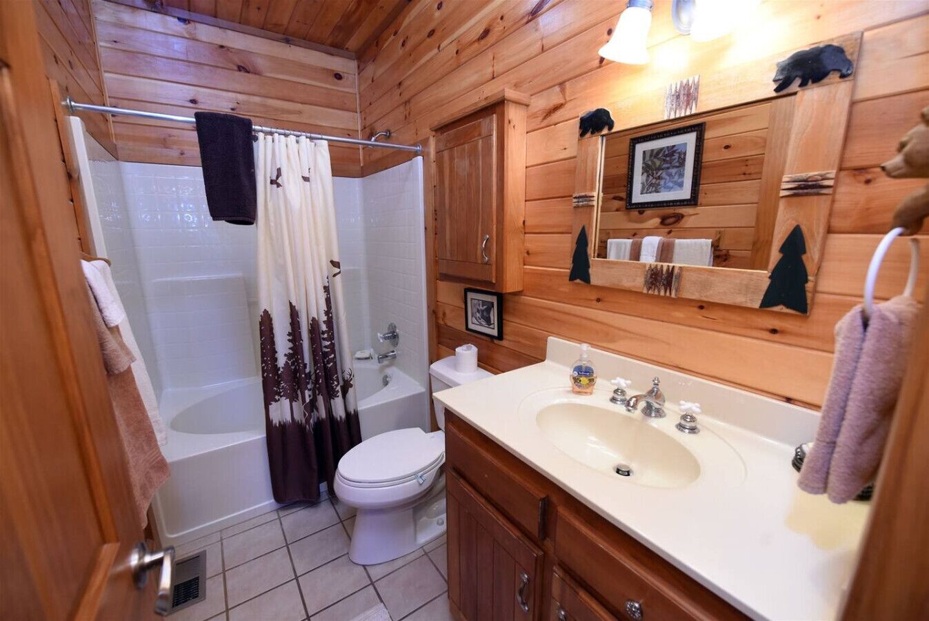 Une salle de bain rustique, avec une cabine en bois, une baignoire, des toilettes et un lavabo.