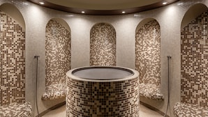 A circular hot tub with mosaic tile walls and benches, surrounded by arched niches. - Hotel Nabokov (Marianske Lazne)