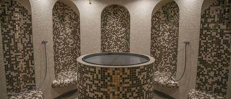 Una bañera de hidromasaje circular con paredes y asientos de mosaicos.