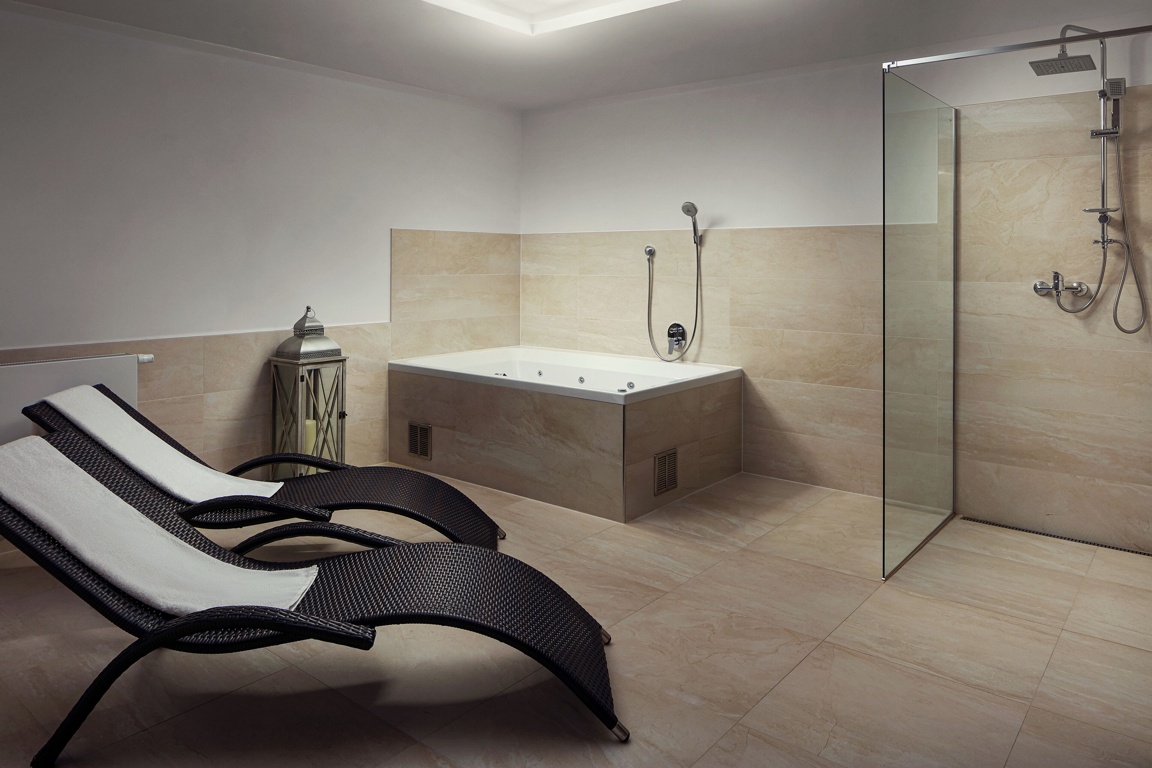 Une salle de bain moderne dotée d’une douche à parois de verre, d’une baignoire sur pieds et de deux fauteuils de relaxation.