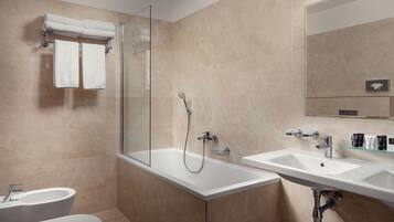 A modern bathroom with a glass-enclosed shower, a freestanding bathtub, a toilet, and a sink with a mirror above.