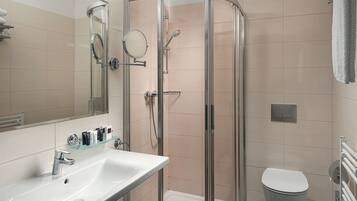A bathroom with a glass-enclosed shower, a white sink, and a toilet.