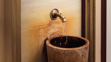A wooden water fountain with a brass spout and a date sign above it.
