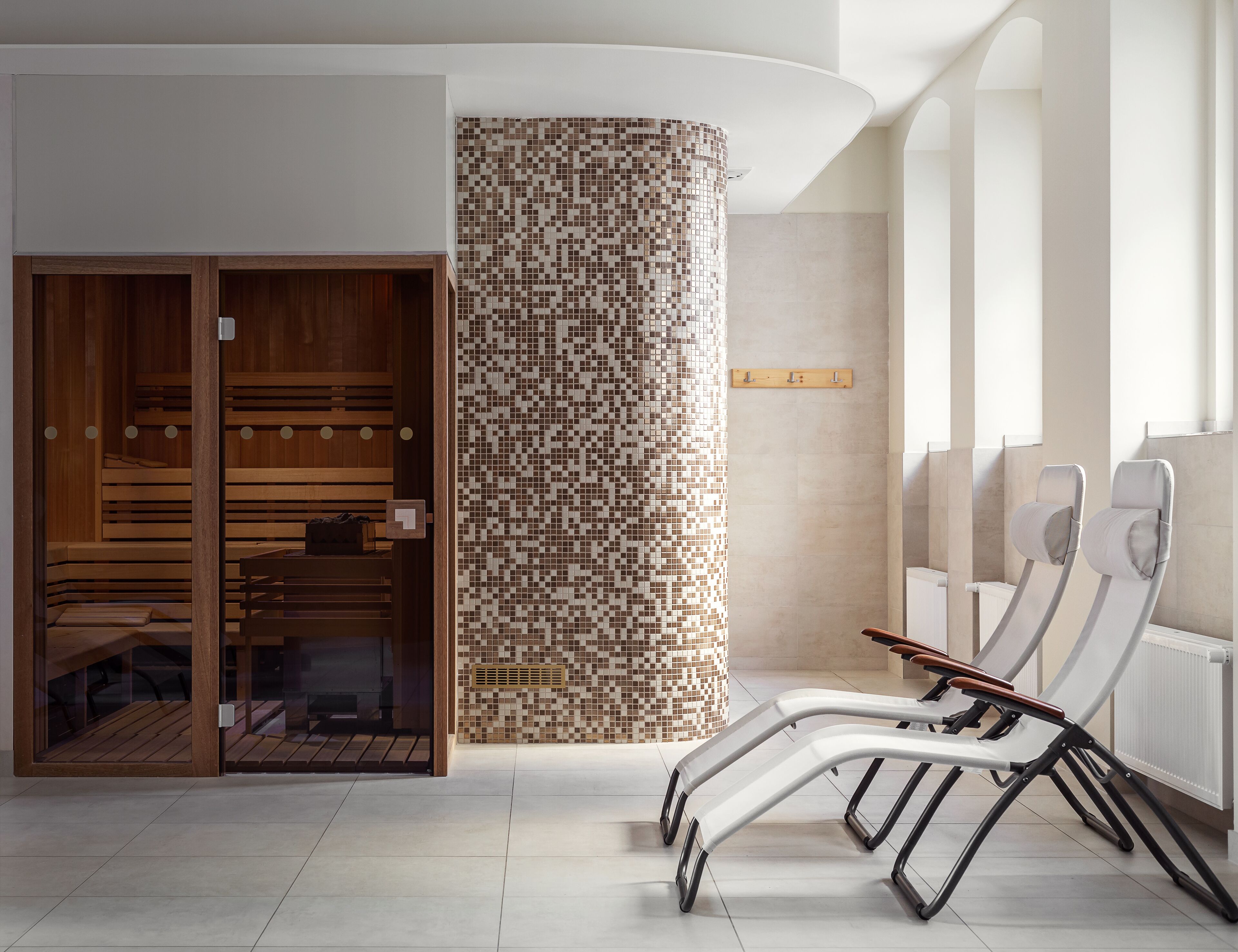 A spa area with wooden benches, a mosaic wall, and a seating area with recliners.