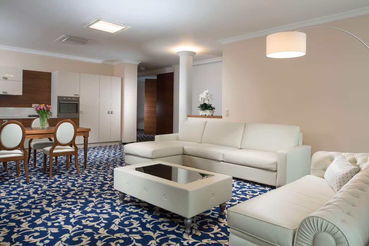 A modern living room with a sofa, a coffee table, and a dining area with chairs and a table.