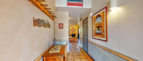 A hallway with a wooden bench, a wall-mounted clock, and a framed picture.