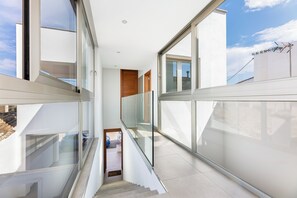 A modern interior with a glass balustrade, a staircase, and a view of the sky.