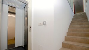 Een trap met beige treden en een leuning, leidend naar een plateau met een lichtschakelaar en stopcontacten.