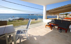Un balcon avec vue sur la mer, un canapé, une table avec une lanterne et une chaise.